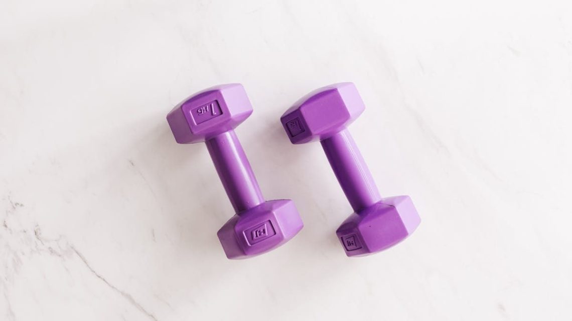 Top view of purple unit cast dumbbell of seven kilo weight placed on white marble surface